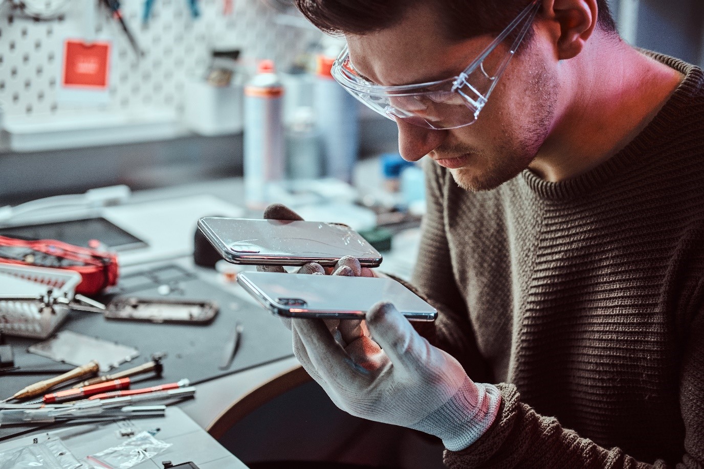 Techniker bei der Handyreparatur – Vergleich eines defekten und eines neuen Smartphones